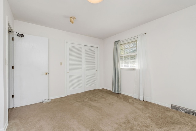 unfurnished bedroom with a closet and light colored carpet