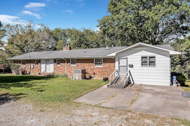 back of property featuring central air condition unit and a lawn