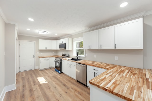 kitchen featuring white cabinets, appliances with stainless steel finishes, sink, and wooden counters