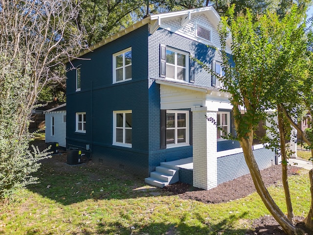 view of side of property with a lawn and central AC unit