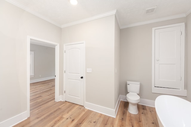 bathroom featuring ornamental molding, a textured ceiling, hardwood / wood-style flooring, and toilet