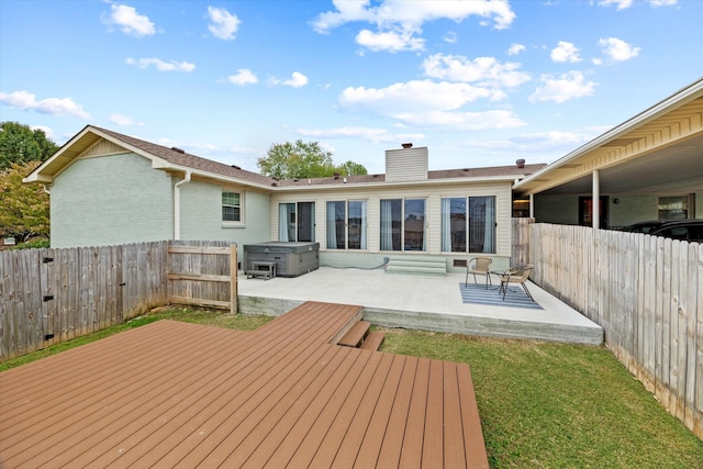 rear view of house with a hot tub, a patio, a lawn, and a wooden deck