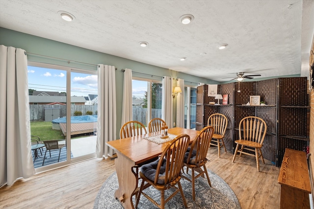 dining space featuring light hardwood / wood-style flooring, a textured ceiling, and ceiling fan