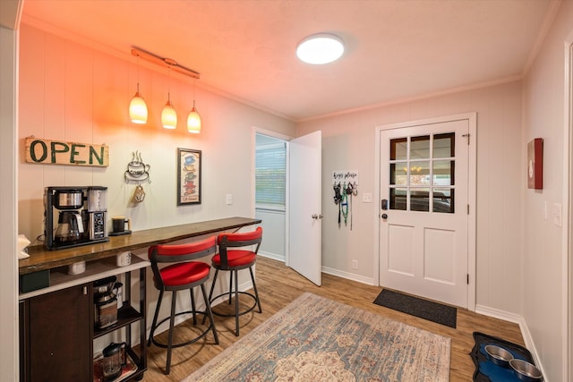 bar featuring ornamental molding, decorative light fixtures, and wood-type flooring