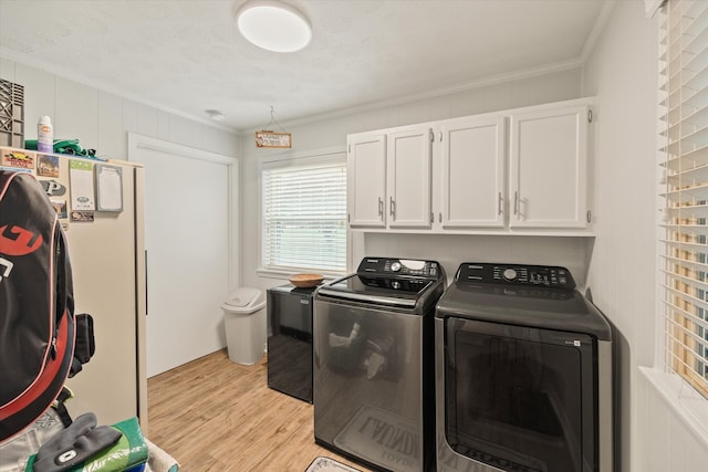 laundry room with cabinets, washer and dryer, a textured ceiling, light hardwood / wood-style flooring, and crown molding