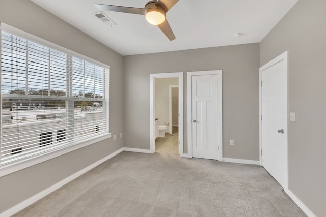 unfurnished bedroom with light carpet, ensuite bathroom, and ceiling fan