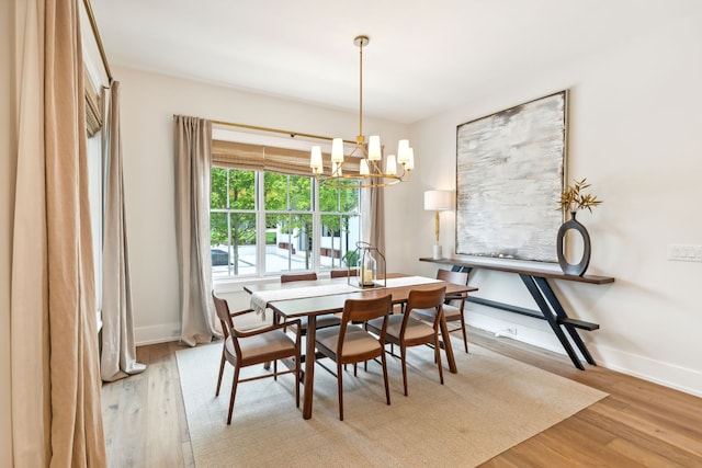 dining space with light hardwood / wood-style flooring and a notable chandelier