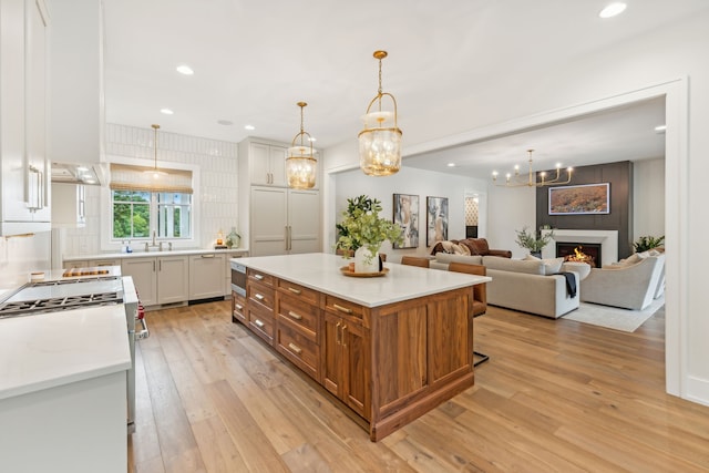 kitchen with white cabinetry, hanging light fixtures, light wood-type flooring, and a kitchen island