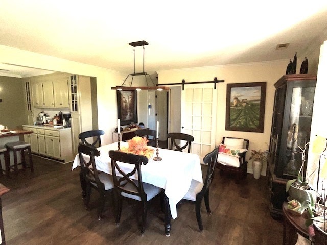 dining room featuring a barn door and dark hardwood / wood-style floors