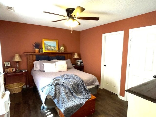 bedroom featuring dark hardwood / wood-style flooring, a textured ceiling, and ceiling fan