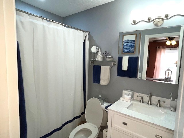 bathroom featuring a shower with shower curtain, ceiling fan, a textured ceiling, vanity, and toilet