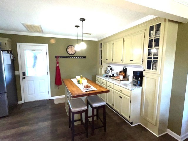 kitchen featuring dark wood-type flooring, stainless steel refrigerator, and crown molding