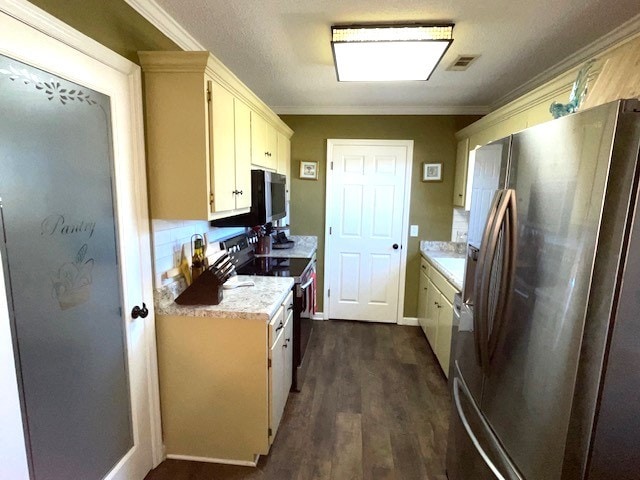 kitchen featuring stainless steel appliances, cream cabinets, dark hardwood / wood-style flooring, and ornamental molding