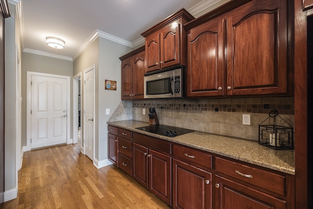 kitchen featuring decorative backsplash, stainless steel microwave, ornamental molding, black electric cooktop, and light wood-style floors