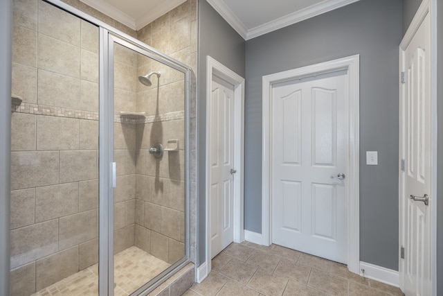 bathroom with a shower stall, baseboards, crown molding, and tile patterned floors