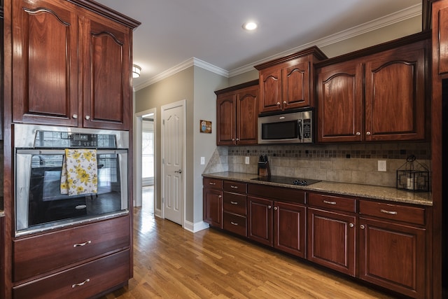 kitchen featuring crown molding, stainless steel appliances, backsplash, light wood-style floors, and baseboards