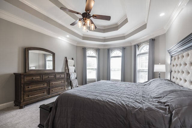 bedroom with light carpet, a ceiling fan, baseboards, ornamental molding, and a tray ceiling