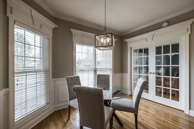 dining area featuring ornamental molding, french doors, wood finished floors, and wainscoting