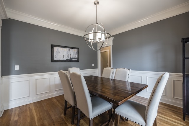 dining space with crown molding, wainscoting, dark wood finished floors, and an inviting chandelier