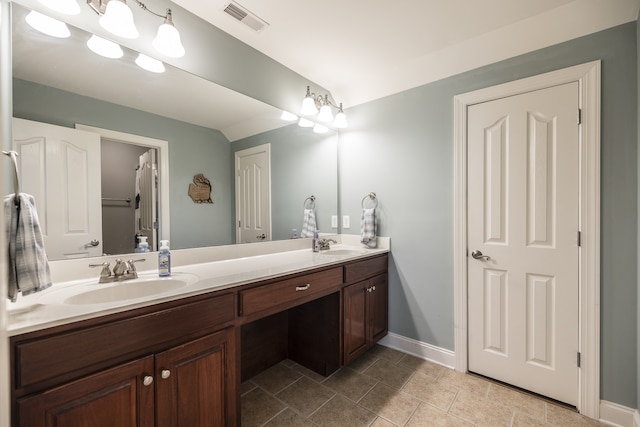 bathroom featuring double vanity, a sink, visible vents, and baseboards