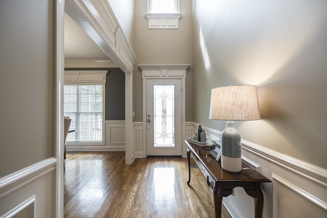 entrance foyer featuring wainscoting, crown molding, and wood finished floors