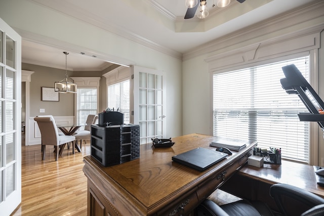 home office with light wood-type flooring, a ceiling fan, crown molding, and wainscoting