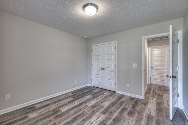 unfurnished bedroom featuring dark wood-type flooring, a closet, and a textured ceiling