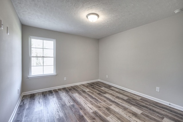 empty room featuring dark wood-type flooring and a textured ceiling