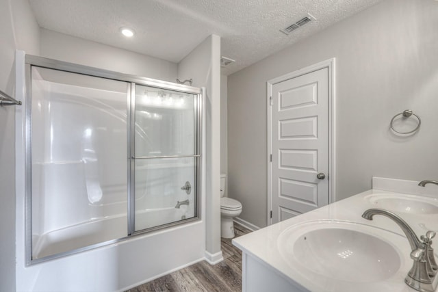 full bathroom with toilet, bath / shower combo with glass door, a textured ceiling, vanity, and hardwood / wood-style flooring