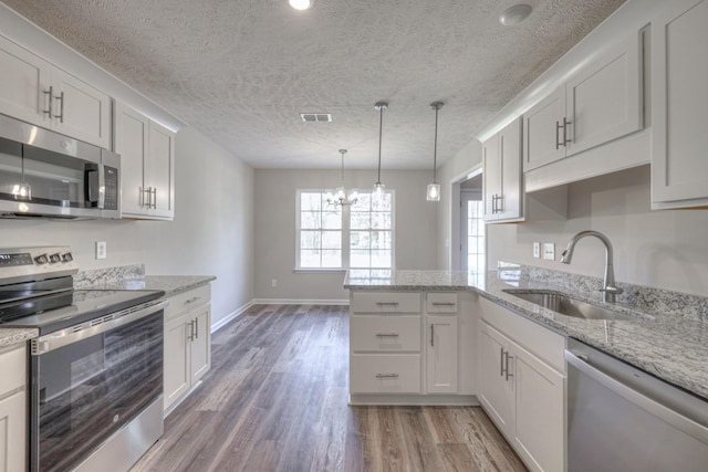 kitchen featuring pendant lighting, sink, white cabinets, kitchen peninsula, and stainless steel appliances