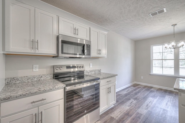 kitchen featuring stainless steel appliances, white cabinetry, light stone counters, and light hardwood / wood-style flooring