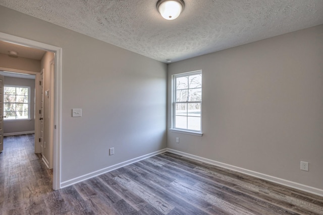 unfurnished room featuring dark wood-type flooring and a textured ceiling