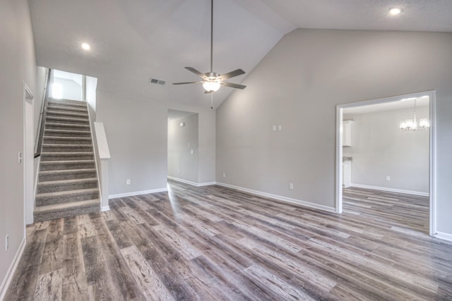 unfurnished living room with hardwood / wood-style flooring, ceiling fan with notable chandelier, and high vaulted ceiling