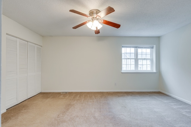 unfurnished bedroom with a textured ceiling, light colored carpet, and ceiling fan