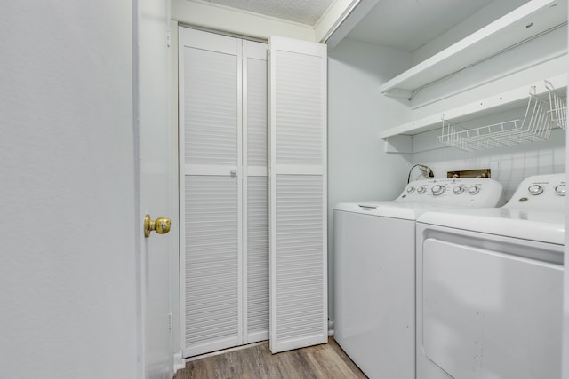 clothes washing area with wood-type flooring and washer and clothes dryer