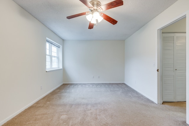 spare room featuring ceiling fan, a textured ceiling, and light colored carpet