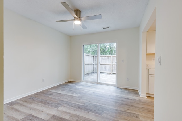 spare room with ceiling fan, a textured ceiling, and light wood-type flooring