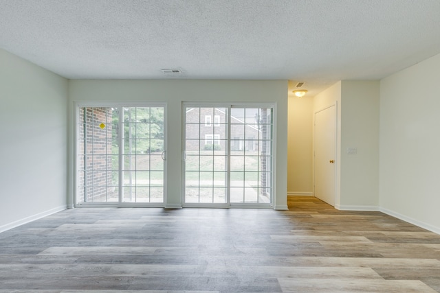 spare room with light hardwood / wood-style floors and a textured ceiling