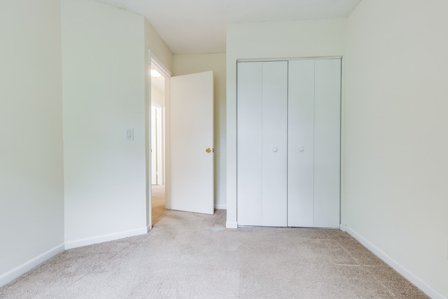 unfurnished bedroom with a closet and light carpet