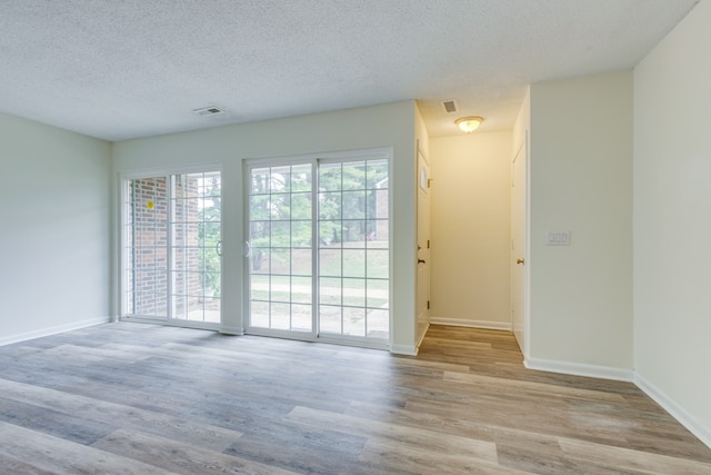 empty room with a textured ceiling and light hardwood / wood-style floors