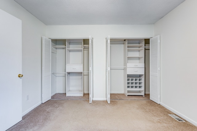 unfurnished bedroom with multiple closets, a textured ceiling, and carpet floors