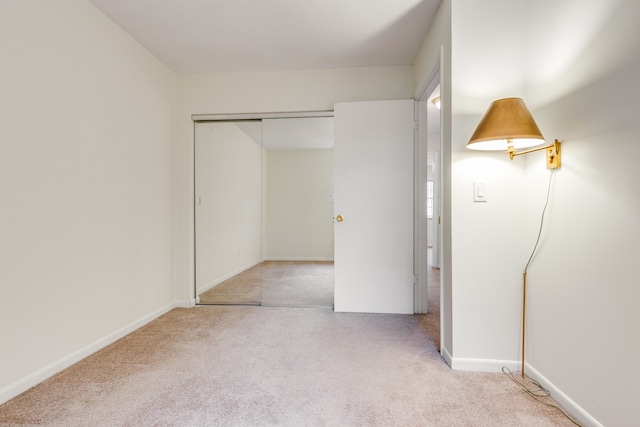 unfurnished bedroom featuring light colored carpet and a closet