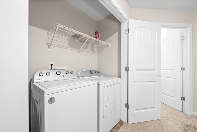 clothes washing area with washing machine and clothes dryer and light colored carpet