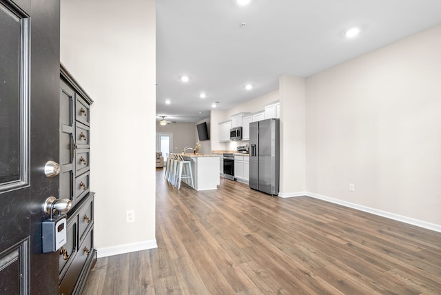 kitchen featuring a kitchen breakfast bar, white cabinets, stainless steel appliances, and dark hardwood / wood-style floors