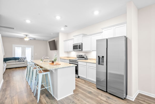 kitchen featuring appliances with stainless steel finishes, white cabinets, sink, and an island with sink