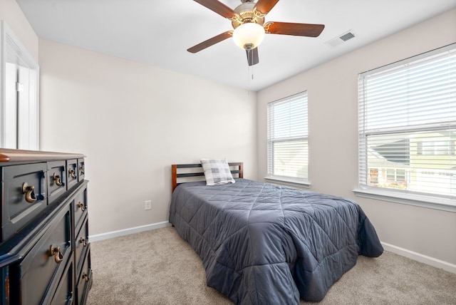 bedroom with light carpet, multiple windows, and ceiling fan