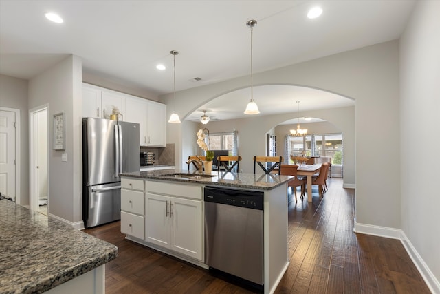 kitchen with white cabinets, an island with sink, appliances with stainless steel finishes, dark hardwood / wood-style floors, and pendant lighting