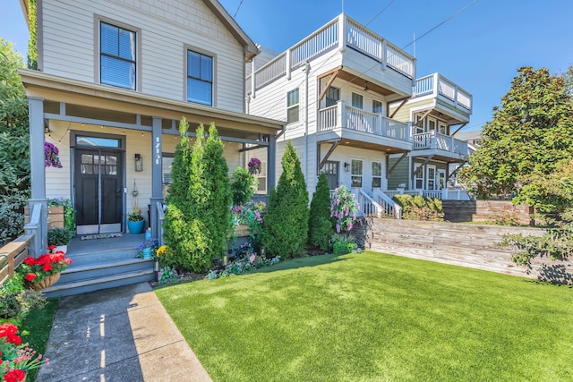 view of front of house with covered porch, a front yard, and a balcony