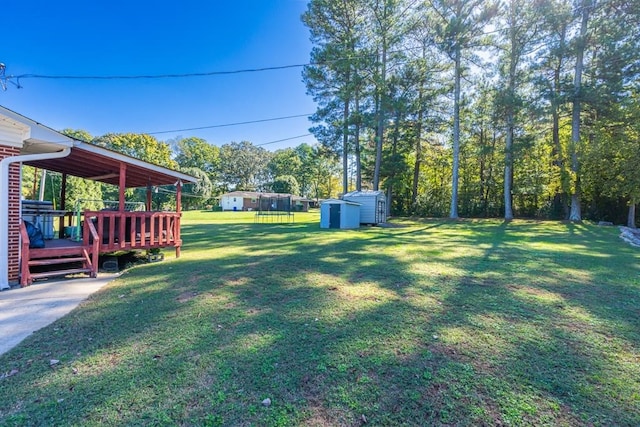 view of yard featuring a wooden deck and a storage shed