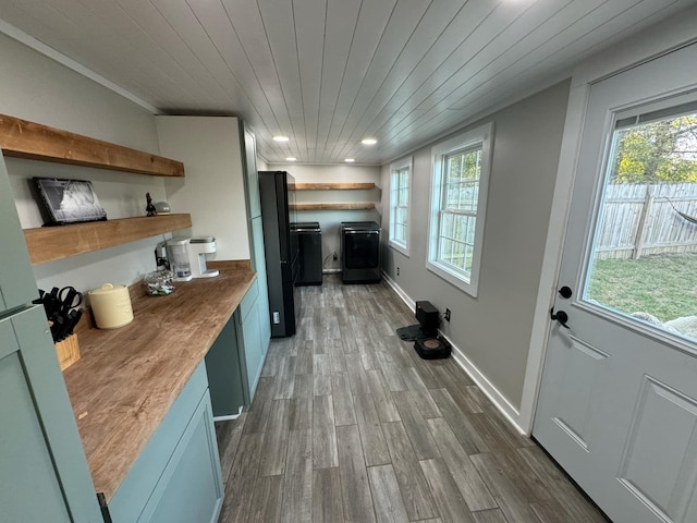 kitchen with wood counters, wooden ceiling, dark wood-type flooring, crown molding, and black refrigerator